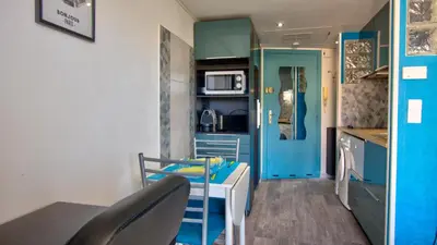 a small kitchen with blue cabinets and a table and chairs at 3 StarsStudio54 23 Ave Laugier100m Plages Mistral in Cannes