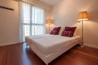 a white bedroom with a bed and a window at Carlton Riviera Cannes in Cannes