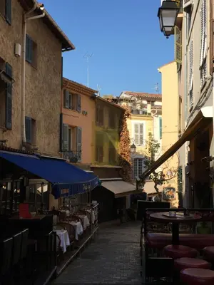 an alley with tables and chairs and buildings at les terrasses du Suquet in Cannes