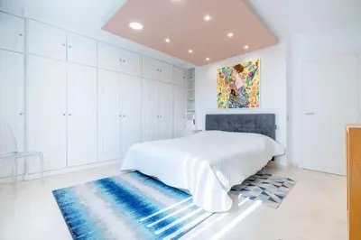 a white bedroom with a bed and a blue rug at 2-Bedroom apartment in Grand Hotel in Cannes
