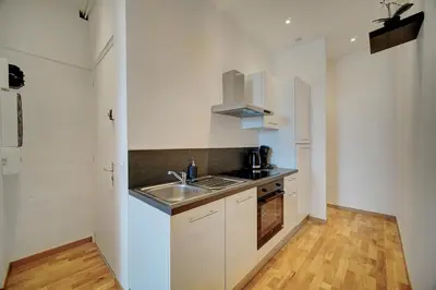 a kitchen with white cabinets and a sink and a counter at Le ART - 500m des plages - Clim - Verrière Côte d'Azur in Cannes