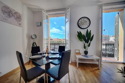 a dining room with a table and chairs and a clock at Le ART - 500m des plages - Clim - Verrière Côte d'Azur in Cannes
