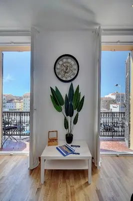 a white room with a clock and a table with a plant at Le ART - 500m des plages - Clim - Verrière Côte d'Azur in Cannes