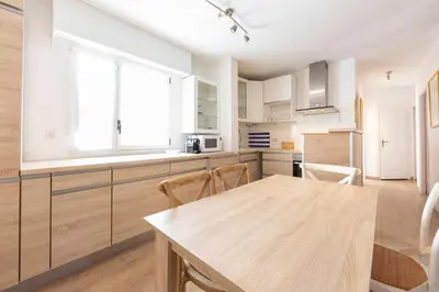 a kitchen with white cabinets and a wooden table at Paradise Cannes Center with Pool and Park VILLA LE LYS in Cannes