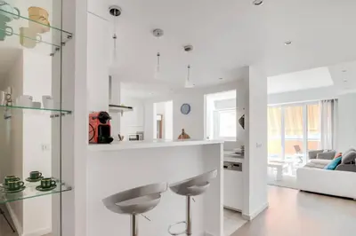 a white kitchen with a bar and a living room at C066-Luxurious apartment with sea view - Cannes in Cannes