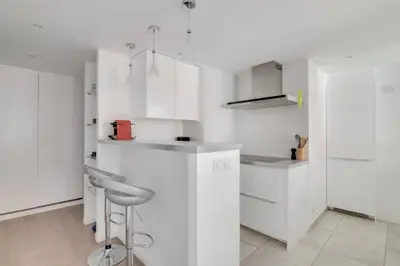 a white kitchen with white cabinets and a stool at C066-Luxurious apartment with sea view - Cannes in Cannes