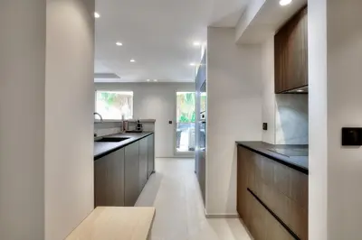 a kitchen with white walls and wooden cabinets at Luxury flat with balcony - city center Cannes in Cannes