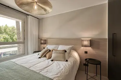 a bedroom with a white bed with a large window at Luxury flat with balcony - city center Cannes in Cannes