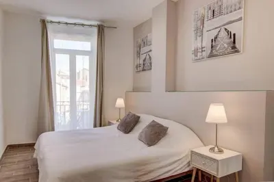 a bedroom with a white bed and a window at Palais Apartment in Cannes