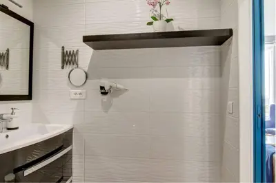a white bathroom with a sink and a mirror at Palais Apartment in Cannes