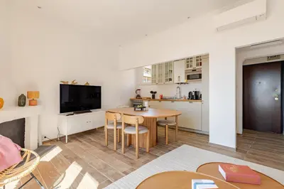 a living room with a table and a kitchen at Splendide 80m2 - 2 Chambres - 5,10min Plages & Gare & Palais des Festivals - Air conditionné in Cannes