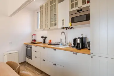 a kitchen with white cabinets and a wooden counter top at Splendide 80m2 - 2 Chambres - 5,10min Plages & Gare & Palais des Festivals - Air conditionné in Cannes