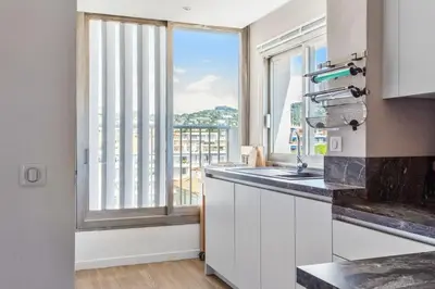 a kitchen with a sink and a large window at Le Panoramique Croisette - Welkeys in Cannes