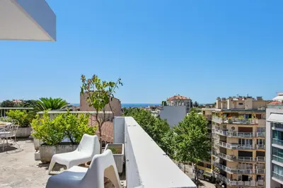 a balcony with white chairs and a view of buildings at Le Panoramique Croisette - Welkeys in Cannes