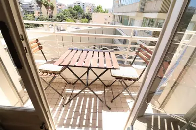 a wooden table and chairs on a balcony at 1 Bedroom Henri IV on the Croisette 240 in Cannes