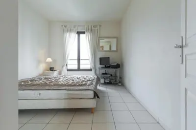 a white bedroom with a bed and a window at Cannes centre 2mins from beach stunning 3-Bed Apt in Cannes