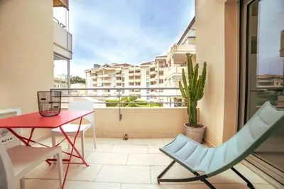 a balcony with a red table and a chair and a table at Les Palmiers in Cannes