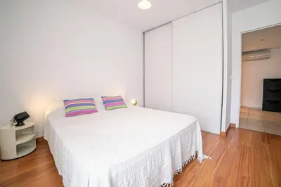 a white bedroom with a large white bed with two pillows at Les Palmiers in Cannes