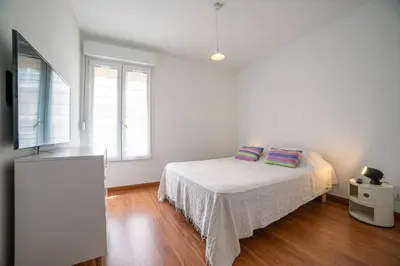 a white bedroom with a bed and two windows at Les Palmiers in Cannes