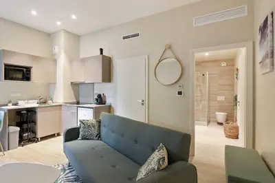 a living room with a couch and a kitchen at Appartement des Anges - Welkeys in Cannes