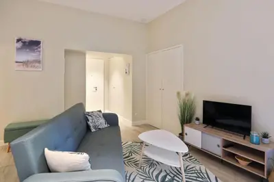 a living room with a blue couch and a tv at Appartement des Anges - Welkeys in Cannes