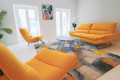 a living room with orange furniture and a table and chairs at NAPOLEON Luxurious renovated apartment 1min from Palais in Cannes