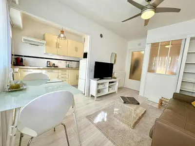 a kitchen and living room with a table and a couch at Magnifique appartement Cosy Cannes à 5mn du fameux palais du festival et ses plages in Cannes