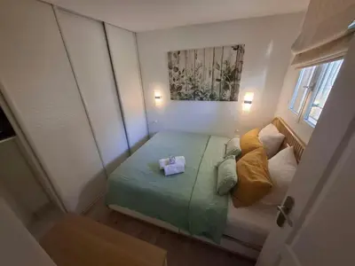 a small bedroom with a green bed with two pillows at Cannes & More in Cannes