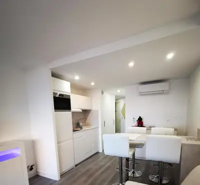 a kitchen with white cabinets and a table and chairs at Appartement en bord de mer in Cannes