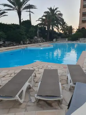 a swimming pool with two lounge chairs and a table at Appartement en bord de mer in Cannes