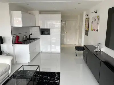 a kitchen with white cabinets and a living room at Ibis croisette in Cannes