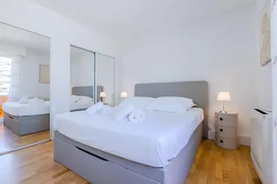 a white bedroom with two beds and a large mirror at Stylish 1-Bedroom Apartment Close to Beaches in Cannes