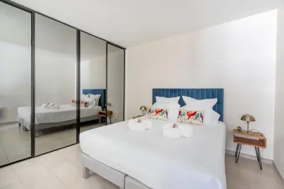 a bedroom with a large white bed with mirrored walls at 45 Croisette Apartment - Prime Location - Beach & Palais by Foot - AC in Cannes
