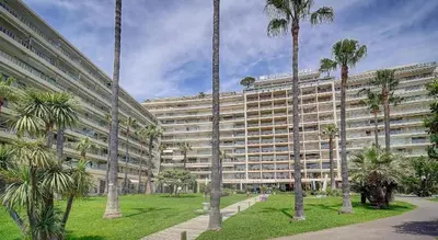 a large building with palm trees in front of it at 45 Croisette Apartment - Prime Location - Beach & Palais by Foot - AC in Cannes