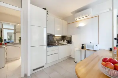 a kitchen with white cabinets and a bowl of fruit on a table at 45 Croisette Apartment - Prime Location - Beach & Palais by Foot - AC in Cannes