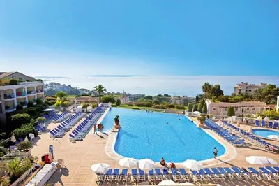 a large swimming pool with blue and white chairs and the ocean at Résidence Cannes Villa Francia - maeva Home - Appartement 2 pièces 4 personnes - Budget MAE-8884 in Cannes