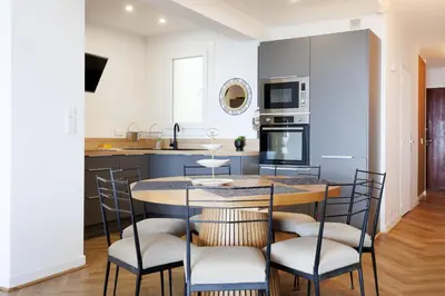 a kitchen with a wooden table with chairs around it at Palais des Iles YourHostHelper in Cannes