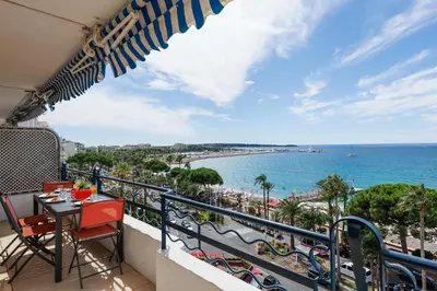 a balcony with a table and chairs and a view of the beach at Palais des Iles YourHostHelper in Cannes