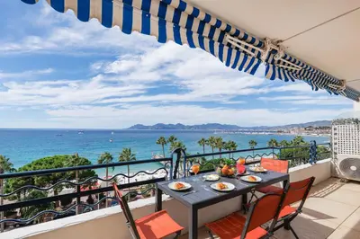 a table on a balcony with a view of the ocean at Palais des Iles YourHostHelper in Cannes