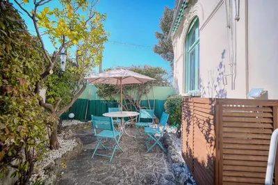 a patio with a table and chairs and an umbrella at IMMOGROOM -Terrace with garden - Quiet - Air-conditioner in Cannes