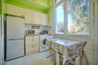 a kitchen with a table and a refrigerator and a window at IMMOGROOM -Terrace with garden - Quiet - Air-conditioner in Cannes