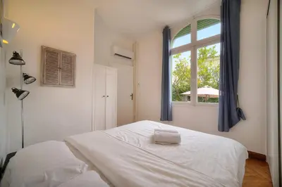 a bedroom with a white bed and a window at IMMOGROOM -Terrace with garden - Quiet - Air-conditioner in Cannes