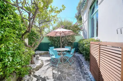 a patio with a table and chairs and an umbrella at IMMOGROOM -Terrace with garden - Quiet - Air-conditioner in Cannes