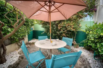 a table and chairs with an umbrella in a garden at IMMOGROOM -Terrace with garden - Quiet - Air-conditioner in Cannes