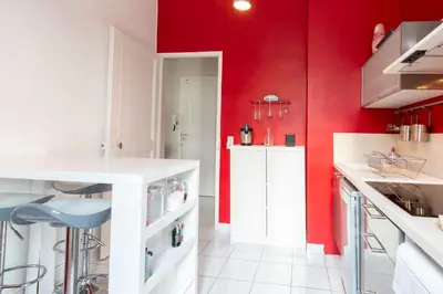 a kitchen with red walls and white counters at Cosy apartment 39M2, two steps from rue d'Antibes and Croisette in Cannes