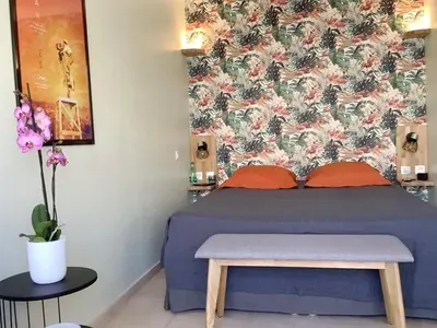 a bedroom with a blue bed with a floral wallpaper at Studio Mimosa Croisette in Cannes