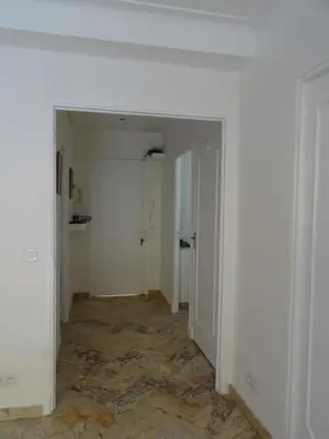 an empty hallway with white walls and an open door at La Rotonde in Cannes