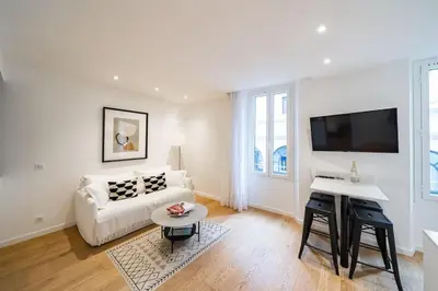 a white living room with a white couch and a tv at Luxury Apartment 100 m to Palais des Festivals in Cannes