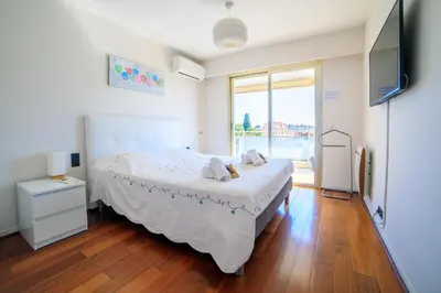 a bedroom with a bed and a large window at Le Prado Parc in Cannes