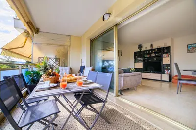 a dining room and living room with a table and chairs at Le Prado Parc in Cannes